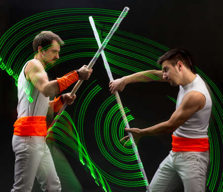 Light trail. Shooting with combined lighting. Young professional athlete plays with lighting equipment on a black background in mixed light. Working out in motion, action. Strength and energy.の写真素材
