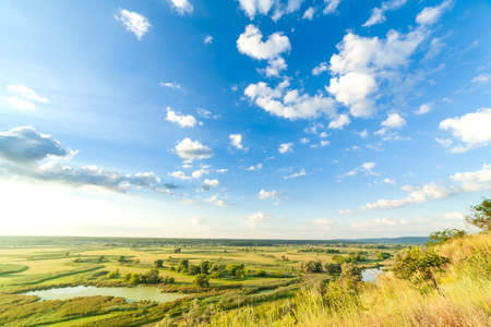 A beautiful valley with a river, blue sky with large clouds and bright sun. Aerial 4K UHDの写真素材