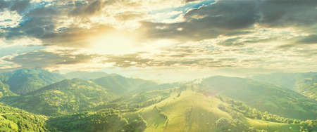 Aerial view of the endless lush pastures of the Carpathian expanses and agricultural land. Cultivated agricultural field. Rural mountain landscape at sunset. Ukraine.の写真素材