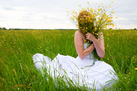 wedding day, beauty, nature concept. in the middle of the field there is an amazing woman wearing white bride dress, she is spinning around herself and sequins are shining in the light of sunの写真素材