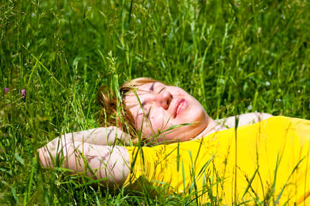 Beautiful healthy Young Woman lying and relaxing on the green grass, subject is blurred