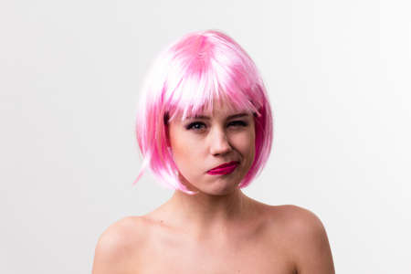Face of a young woman with bright makeup on a pink background with gathered hair in a smooth ponytail.の写真素材