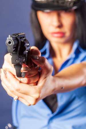 A girl in a uniform with a gun poses in the studio. The emphasis is on the gun, which is in the...