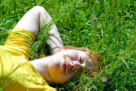 Beautiful healthy Young Woman lying and relaxing on the green grass, subject is blurredの写真素材