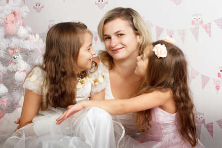 Mother together in the little daughter, sit on a floor near a festive fir-tree, play and consider gifts. Waiting for a holidayの写真素材