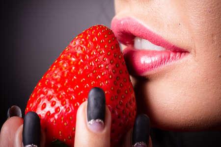 Portrait of a brunette beauty with honey dripping strawberry.の写真素材