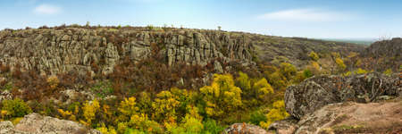 A large number of stone minerals covered with green vegetation lying above a small river in picturesque Ukraine and its beautiful natureの写真素材
