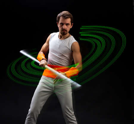 Light trail. Shooting with combined lighting. Young professional athlete plays with lighting equipment on a black background in mixed light. Working out in motion, action. Strength and energy.の写真素材