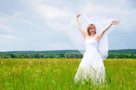 wedding day, beauty, nature concept. in the middle of the field there is an amazing woman wearing white bride dress, she is spinning around herself and sequins are shining in the light of sunの写真素材