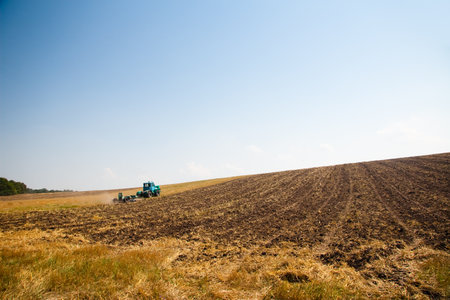 Modern tractor in the field with complex for the plowing. The concept of work in a fields and agriculture industry.の写真素材