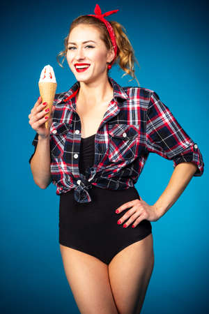 Beautiful pin up stylized young pregnant woman in kitchen drinking juiceの写真素材