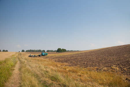 Modern tractor in the field with complex for the plowing. The concept of work in a fields and agriculture industry.の写真素材