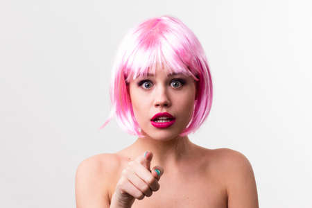Face of a young woman with bright makeup on a pink background with gathered hair in a smooth ponytail.の写真素材