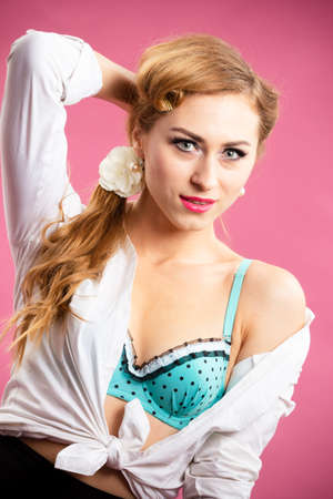 Displeased pin up woman posing with crossed arms on pink backgroundの写真素材