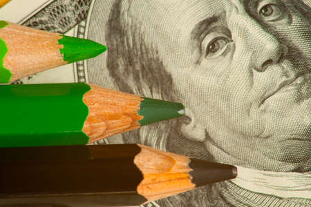 colored pencils and us money in a pink backgroundの写真素材