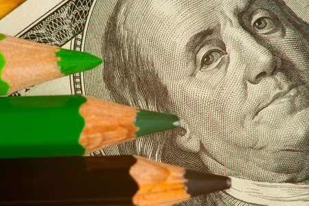 colored pencils and us money in a pink backgroundの写真素材