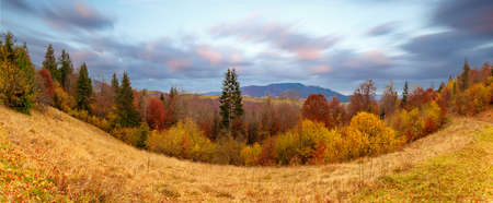Carpathians, Ukraine. Sunset in the cloudy sky over the autumn forest lake. View from shore level,...