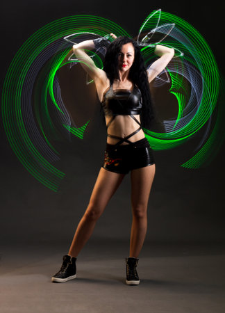 Light trail. Shooting with combined lighting. Young professional athlete plays with lighting equipment on a black background in mixed light. Working out in motion, action. Strength and energy.の写真素材