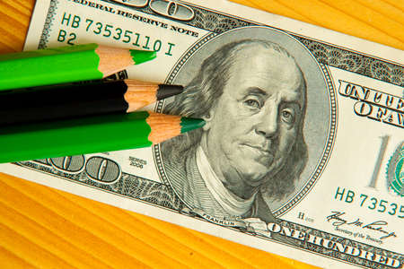 colored pencils and us money in a pink backgroundの写真素材