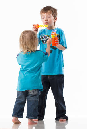 Portrait of a brother and sister, curly blond with blue eyes laughing merrily on a white background. Childrens emotions, happiness, joy, fun. Beautiful cute children. Friendship.の写真素材