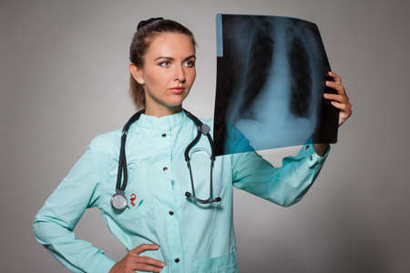 Young beautiful brunette doctor woman wearing stethoscope holding chest xray with a happy face standing and smiling with a confident smile showing teethの写真素材