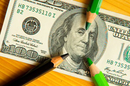 colored pencils and us money in a pink backgroundの写真素材