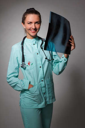 Young beautiful brunette doctor woman wearing stethoscope holding chest xray with a happy face standing and smiling with a confident smile showing teethの写真素材