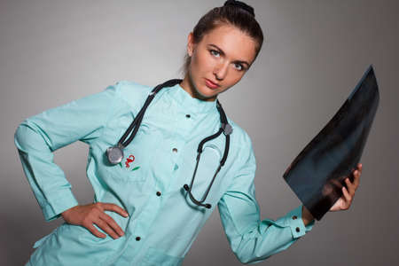 Young beautiful brunette doctor woman wearing stethoscope holding chest xray with a happy face standing and smiling with a confident smile showing teethの写真素材