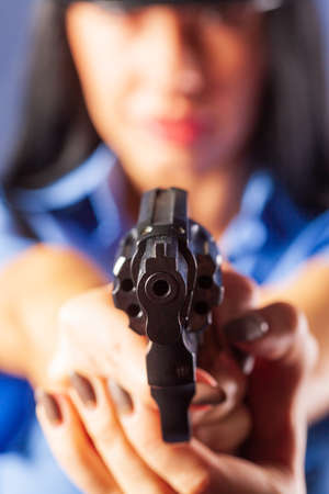 A girl in a uniform with a gun poses in the studio. The emphasis is on the gun, which is in the foreground.の写真素材