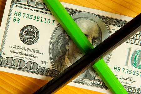 colored pencils and us money in a pink background