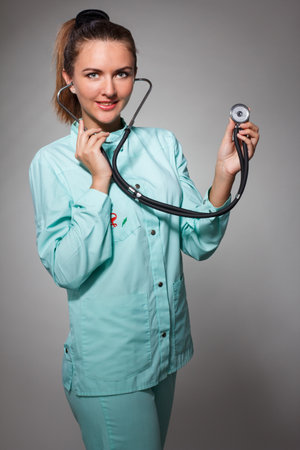 Painful in chest. Focused confident female doctor using stethoscope while diagnosing health and posing on the isolated backgroundの写真素材