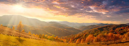 Ukraine. Warm autumn in a village. Picturesque beech, birch and pine forests and Hutsul houses against the backdrop of the Synevyr Pass ridge are very beautiful with bright colors after a fine day.の写真素材