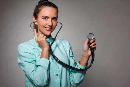 Painful in chest. Focused confident female doctor using stethoscope while diagnosing health and posing on the isolated backgroundの写真素材