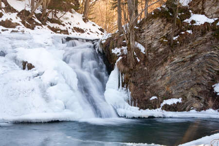 A small active waterfall. Clean mountain stream, snowy winter landscape, wildlife backgroundの写真素材