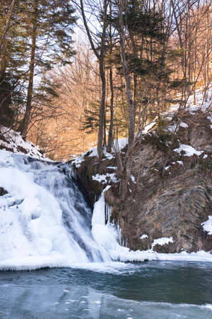 A small active waterfall. Clean mountain stream, snowy winter landscape, wildlife backgroundの写真素材