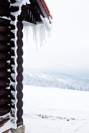 The house from logs with the iced over roof and hanging down icicles.の写真素材