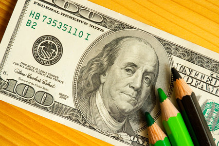 colored pencils and us money in a pink backgroundの写真素材