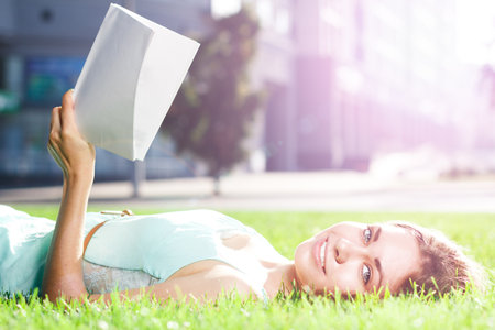 Pretty brunette girl wearing elegant dress relaxing outdoor in green grass and smells aromatic lemon or lime citrusの写真素材