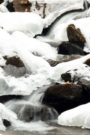 A small active waterfall. Clean mountain stream, snowy winter landscape, wildlife backgroundの写真素材