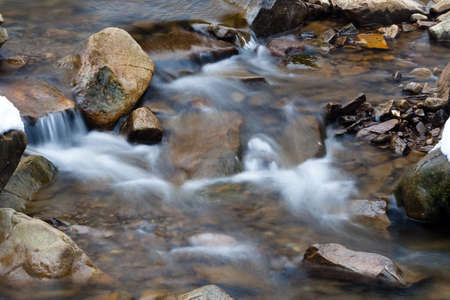 A small active waterfall. Clean mountain stream, snowy winter landscape, wildlife background