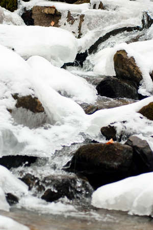 A small active waterfall. Clean mountain stream, snowy winter landscape, wildlife backgroundの写真素材