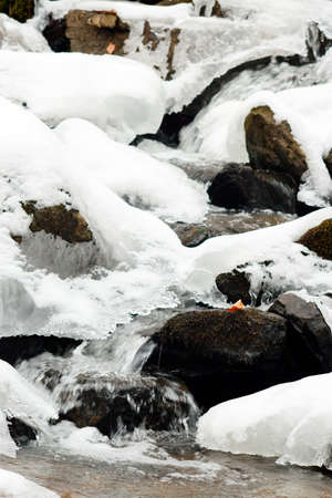 A small active waterfall. Clean mountain stream, snowy winter landscape, wildlife backgroundの写真素材