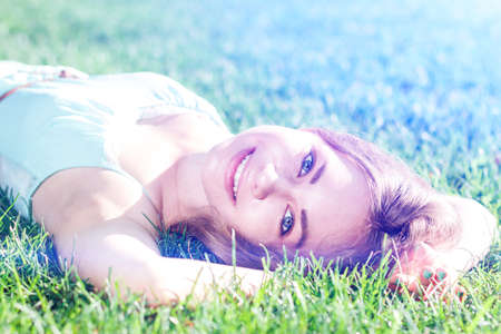 Pretty brunette girl wearing elegant dress relaxing outdoor in green grass and smells aromatic lemon or lime citrusの写真素材