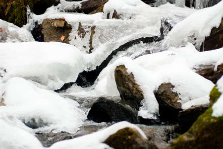 A small active waterfall. Clean mountain stream, snowy winter landscape, wildlife backgroundの写真素材