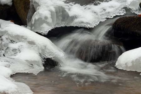 A small active waterfall. Clean mountain stream, snowy winter landscape, wildlife backgroundの写真素材