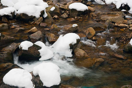 A small active waterfall. Clean mountain stream, snowy winter landscape, wildlife backgroundの写真素材
