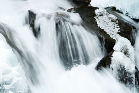 A small active waterfall. Clean mountain stream, snowy winter landscape, wildlife backgroundの写真素材