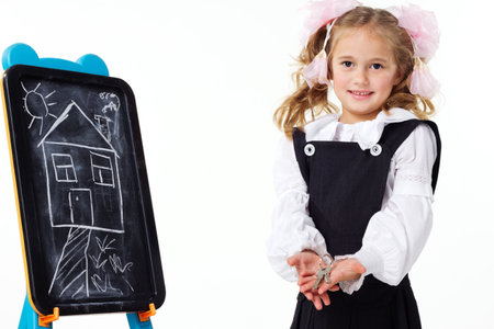 Young girls with a blackboard and a drawing of a new house. In the hands of the girl are the keys to a new home. Concept photo.の写真素材