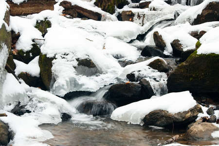 A small active waterfall. Clean mountain stream, snowy winter landscape, wildlife backgroundの写真素材