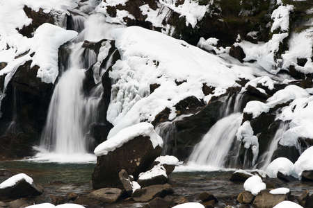 A small active waterfall. Clean mountain stream, snowy winter landscape, wildlife backgroundの写真素材
